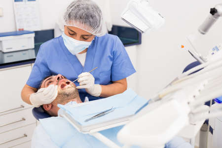 Female dentist in face mask with male patientの写真素材