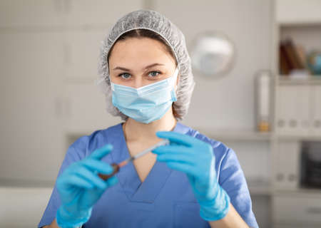 Girl nurse in mask holding syringe for injection in clinicの写真素材