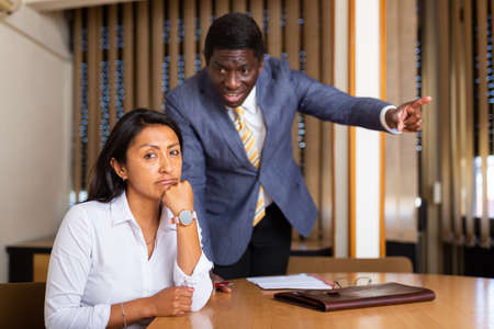 Frustrated woman entrepreneur sitting at office desk with angry partnerの写真素材