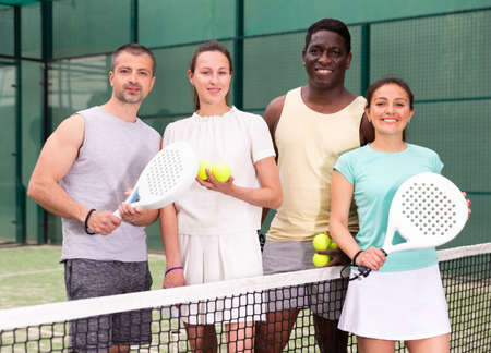 Four paddle tennis players posing on courtの写真素材