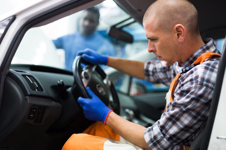 Service engineer in uniform repairs a car steering wheel