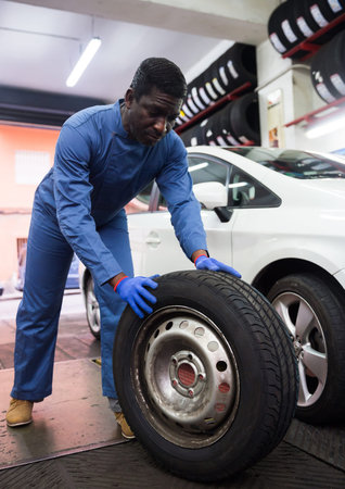 Afro american auto mechanic holds wheel