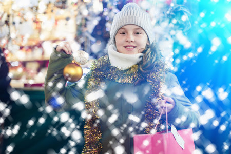 Young girl is demonstraiting decorations for Christmas tree