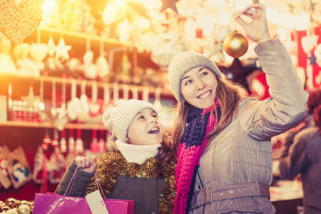Smiling girl with woman are buying toys for X-mas treeの写真素材