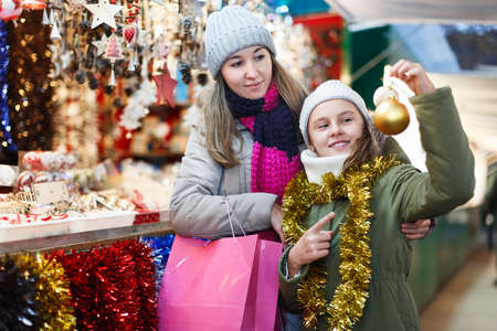 Girl with woman choosing balls on the treeの写真素材