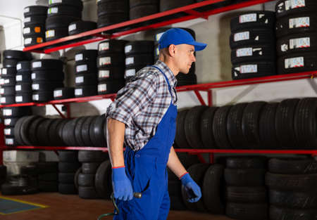 Auto mechanic with a compressor hose in hands in car serviceの写真素材