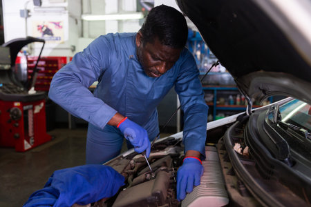 Professional american mechanic man in uniform repairing car engine