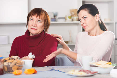 Unhappy adult female quarrel with daughter at tableの写真素材
