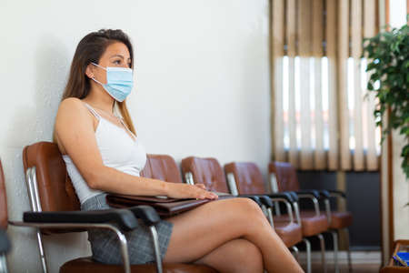 Latino american woman in face mask waiting for job interviewの写真素材