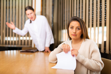 Unhappy woman standing in office after reprimand from chief