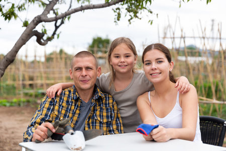 Young family resting after gardening at allotment