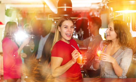 Young women drinking cocktails and talking on party