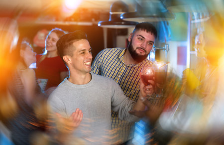 Friends clinking glasses with cocktails at night club