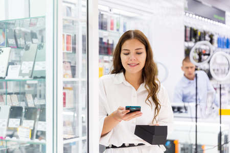 Young woman choosing phone in consumer electronics storeの写真素材