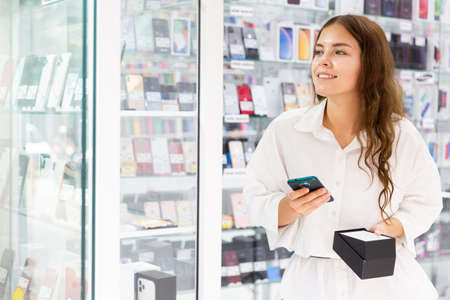 Young woman choosing phone in consumer electronics storeの写真素材