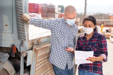 Woman manager in face mask discussing order list with man workerの写真素材