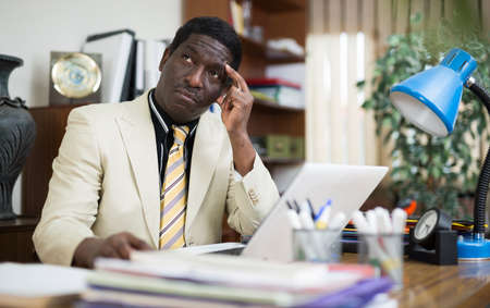 Pensive african american man working in modern officeの写真素材