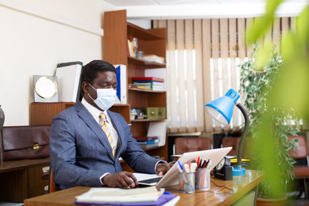 Businessman in protective mask focused on working with laptop