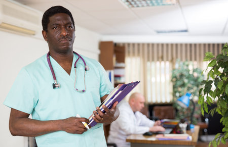 Portrait of male doctor wearing uniform with folder