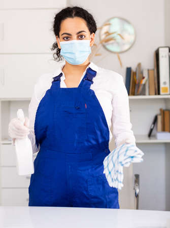 Female office in protective mask cleaner is cleaning dust from the desk in officeの写真素材