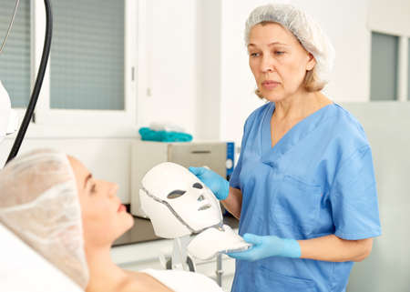 Doctor beautician applies mask to the patient for facial rejuvenationの写真素材