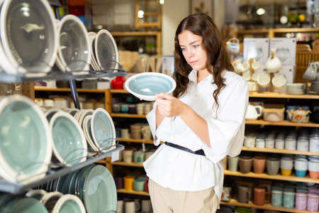 Young woman choosing new dishes at storeの写真素材