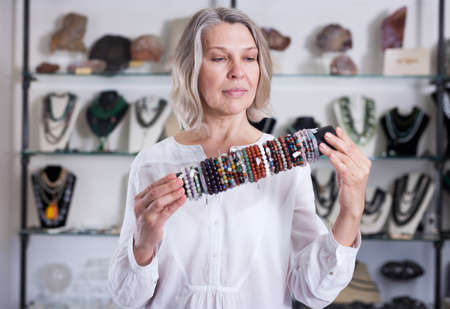 Smiling woman seller offering fashionable bracelets in the storeの写真素材