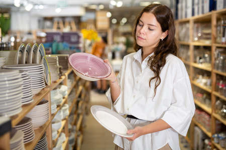 Woman choosing ceramic plates in tableware shopの写真素材