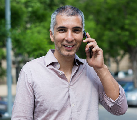 Portrait of male who is standing satisfied near his car and talking by phone