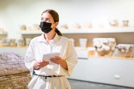Woman in mask visiting exhibit at sculpture hall in museumの写真素材