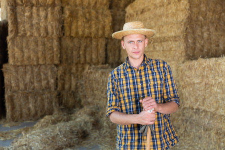 Cow farm owner posing in the barn against backdrop of hay bales