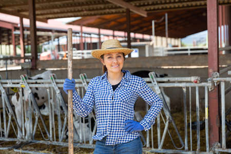 Portrait of a positive young woman standing on a cattle farmの写真素材