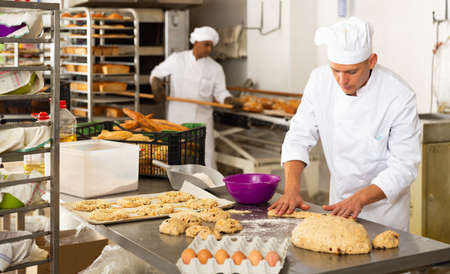 portrait male baker making cookies in bakehouseの写真素材