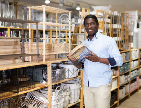 Smiling African American looking for wicker basket at storeの写真素材