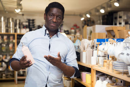 African american man choosing condiment dispenser in household goods storeの写真素材