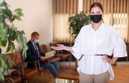 Portrait of a young confident girl in a protective mask standing in the lobbyの写真素材
