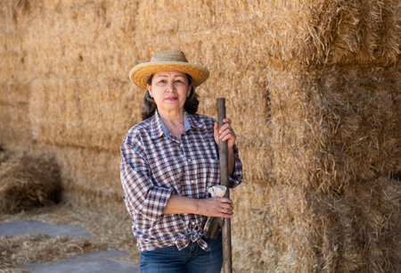 Portrait of an elderly woman farmer, standing near the haystacks