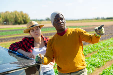 Two farmers talking near car at fieldの写真素材
