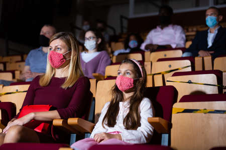 Daughter with mom wearing protective masks watching concertの写真素材