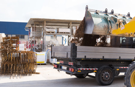 Excavator moving sand to empty truck at hardware store