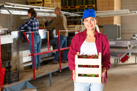 Woman holding sweet cherries at fruit warehouse