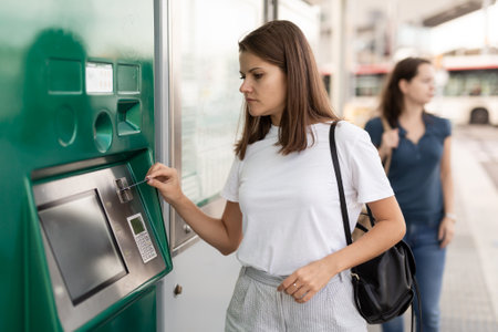 Woman using ticket vending machine at tram stopの写真素材