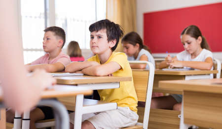 Schoolboy sitting in classroom during lesson in elementary schoolの写真素材