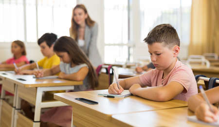 Schoolboy sitting in classroom during lesson in elementary schoolの写真素材
