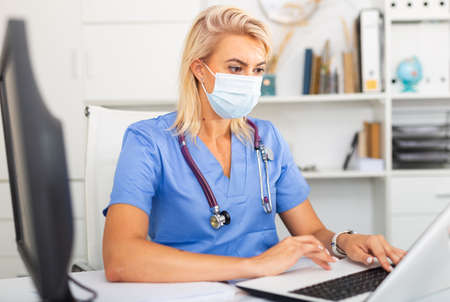 Female worker enters patient data into laptopの写真素材