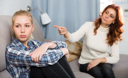 Unhappy women sitting at sofa and talking about problems at homeの写真素材