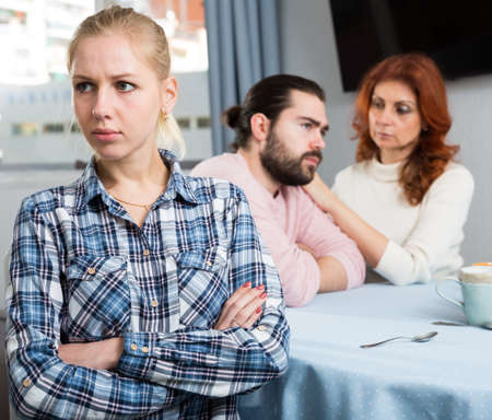 Young spouses and mother-in-low arguing indoorsの写真素材