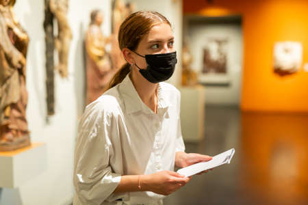 Woman wearing face mask observing artworks in museumの写真素材