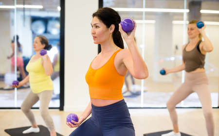 Asian brunette lady doing exercises with pilates ballの写真素材
