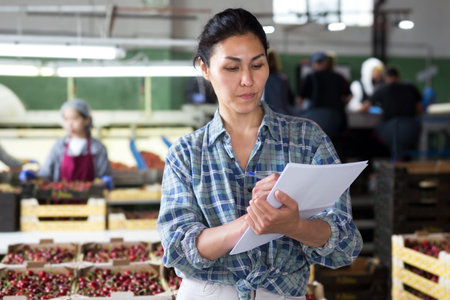Woman controlling process of sorting of fresh ripe cherry on producing line
